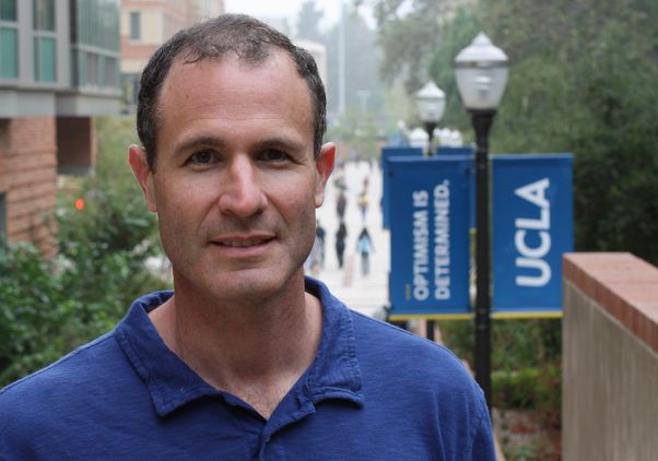 Professor Alan Castel on campus, with Bruin banners in background