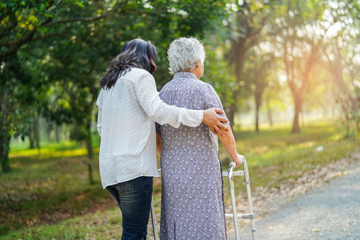 Caregiver helps older woman with walker