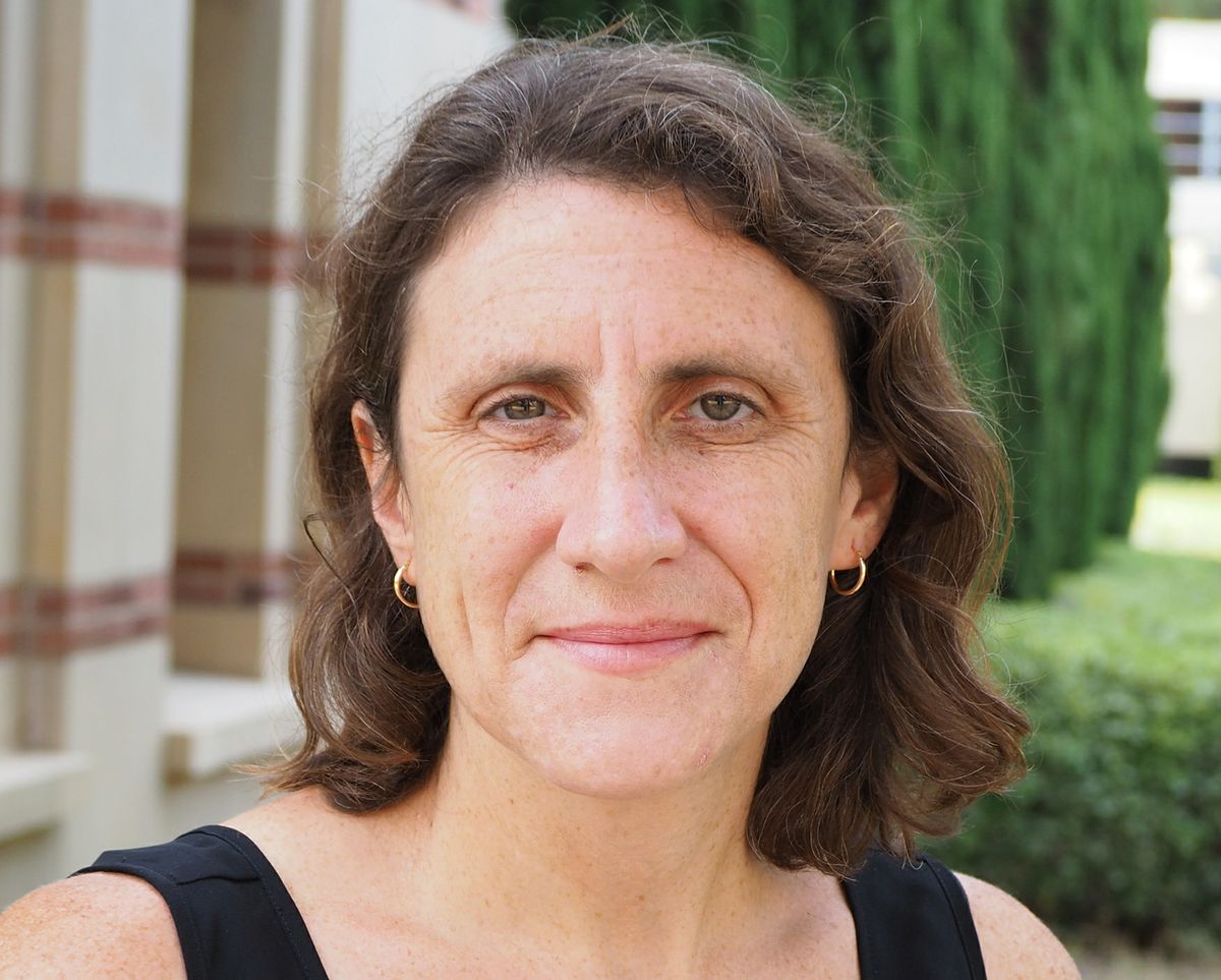 A portrait of Alice Shapley smiling outdoors on a campus setting.