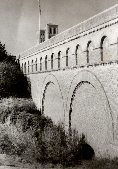 A row of Romanesque “windows” lined each side of the bridge, above three massive arches and mosaic insets. side view of Arroyo Bridge