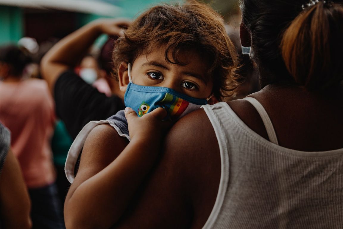 Young child with face mask in mother’s arms