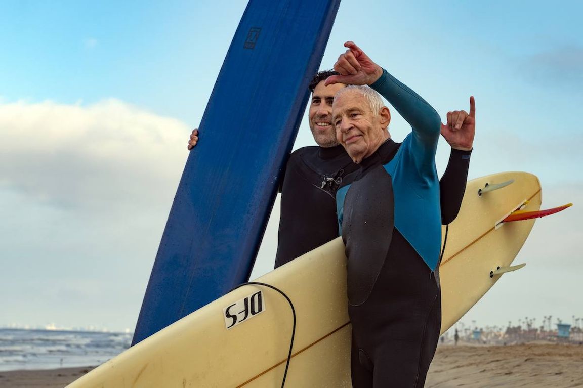Dr. Adam Sassoon and Robert Lombard with surfboards at the beach