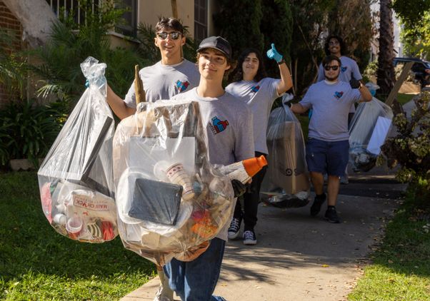 Students carrying trash at neighborhood cleanup