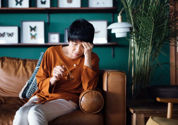 Woman sitting on couch and holding head