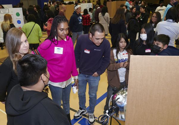 People gather around a research poster presentation