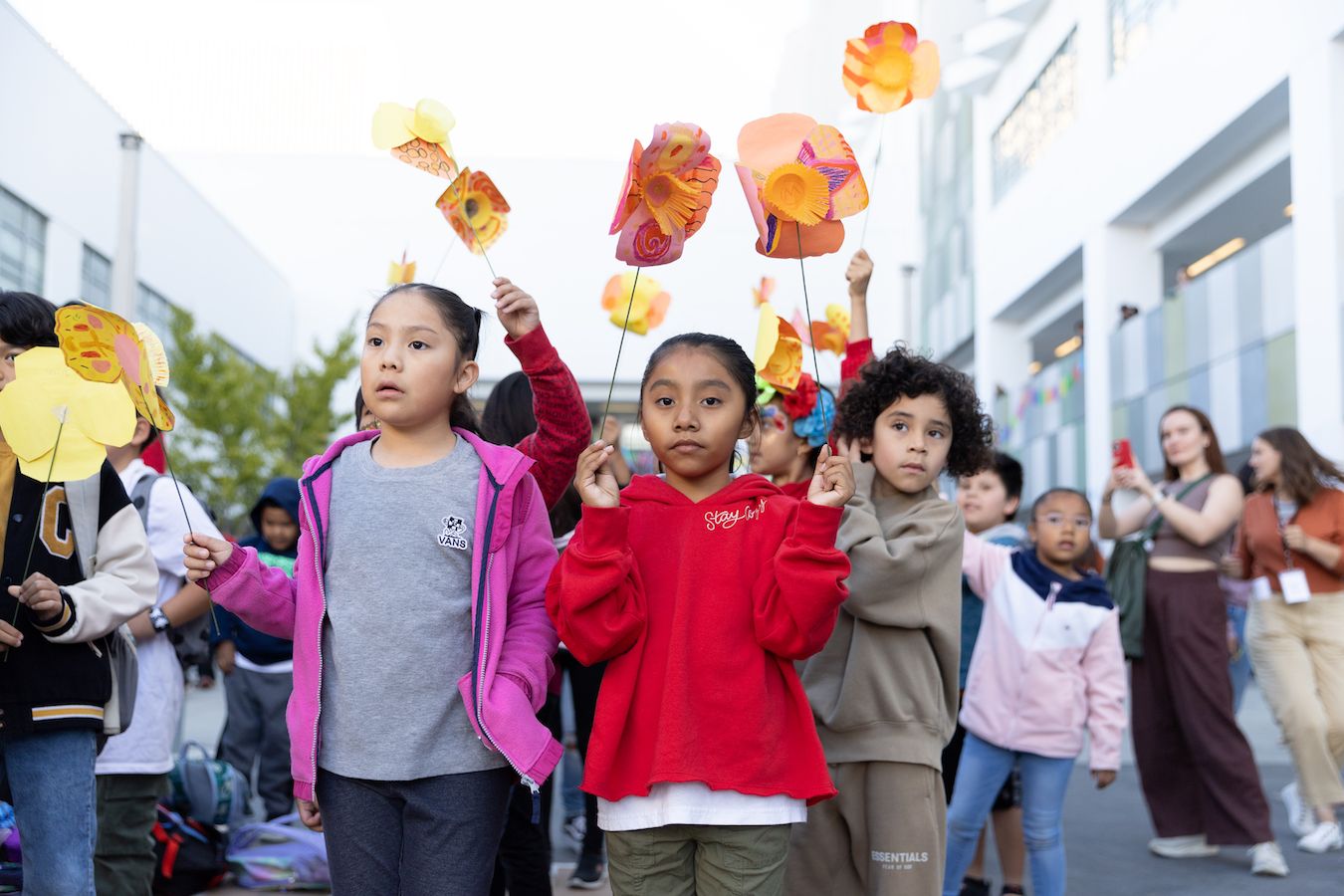 Group of students holding paper poppies for Little Amal and looking upward