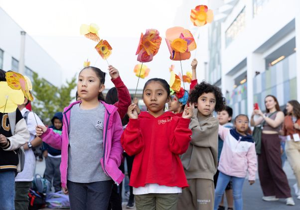 Group of students holding paper poppies for Little Amal and looking upward