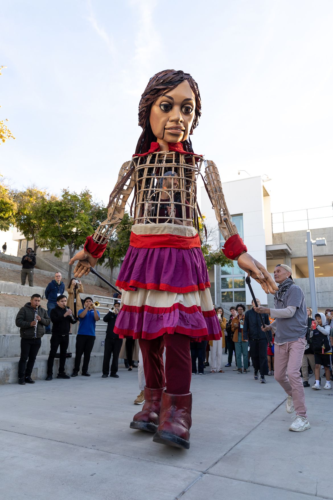 Puppeteers operate ‘Little Amal’ as a band plays Oaxacan music in the background