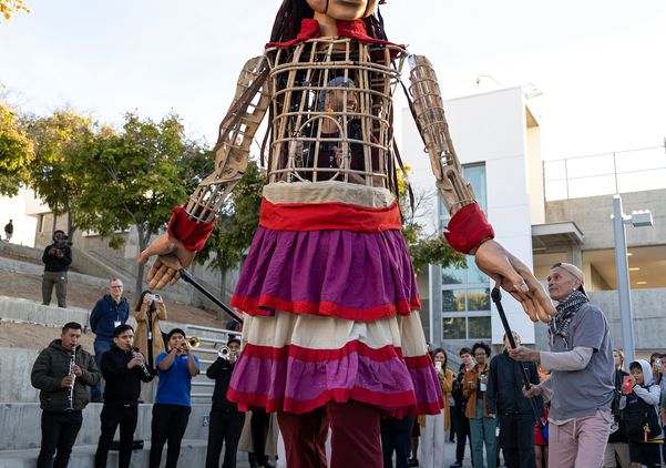 Puppeteers operate ‘Little Amal’ as a band plays Oaxacan music in the background