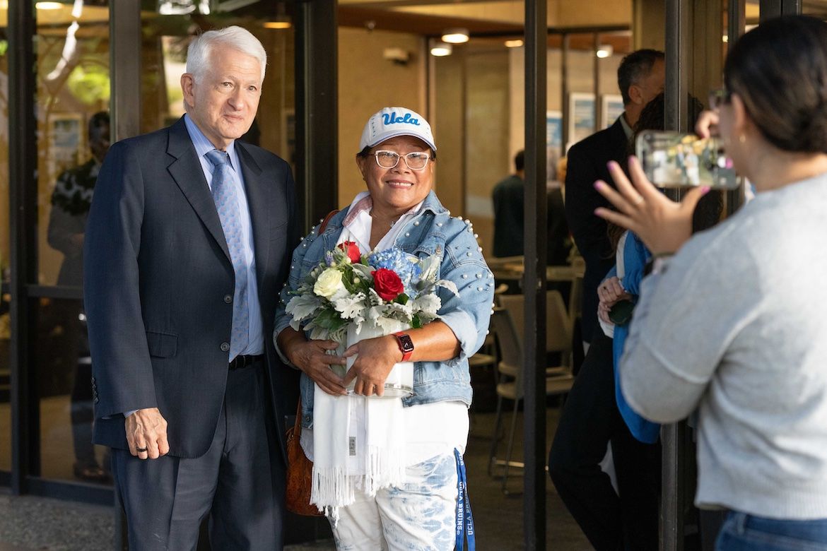 Chancellor Gene Block poses with a woman in a UCLA hat at a campus luncheon honoring veterans