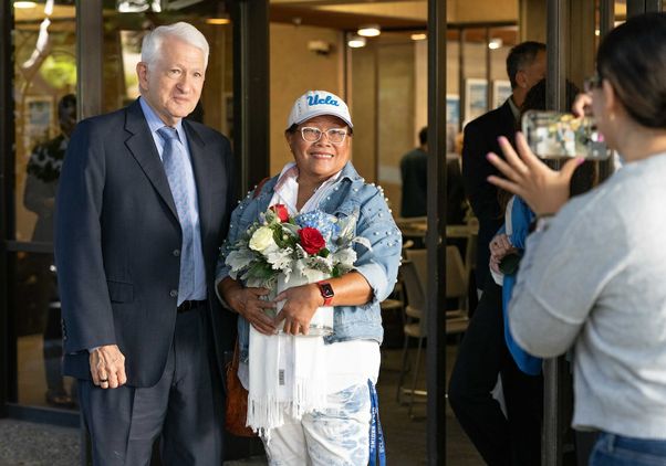 Chancellor Gene Block poses with a woman in a UCLA hat at a campus luncheon honoring veterans