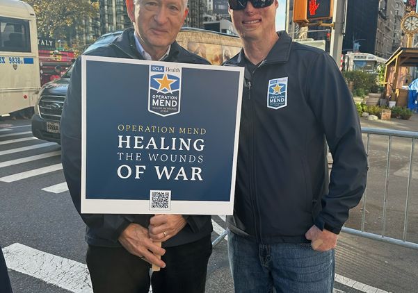 Chancellor Block, holding sign, stands with patient of Operation Mend at the New York City Veterans Day parade