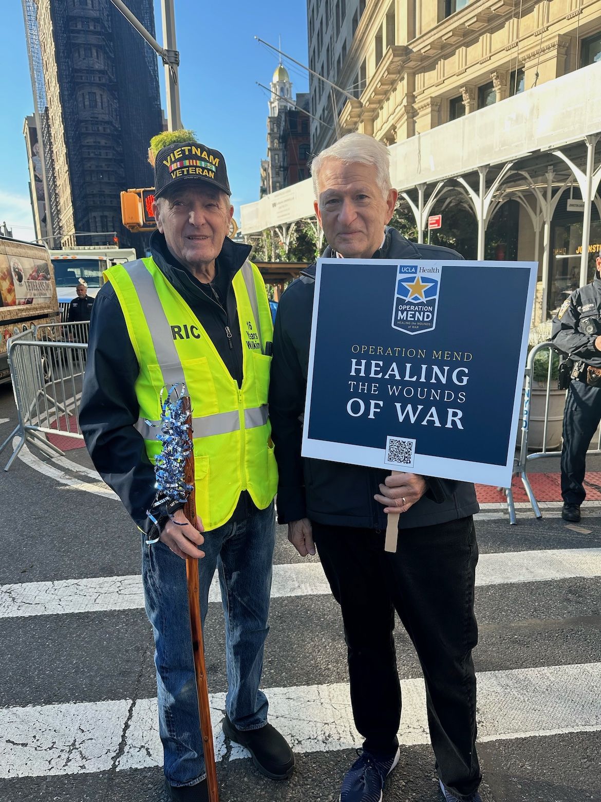 Chancellor Gene Block, holding sign, stands with a military veteran at the New York City Veterans Day parade