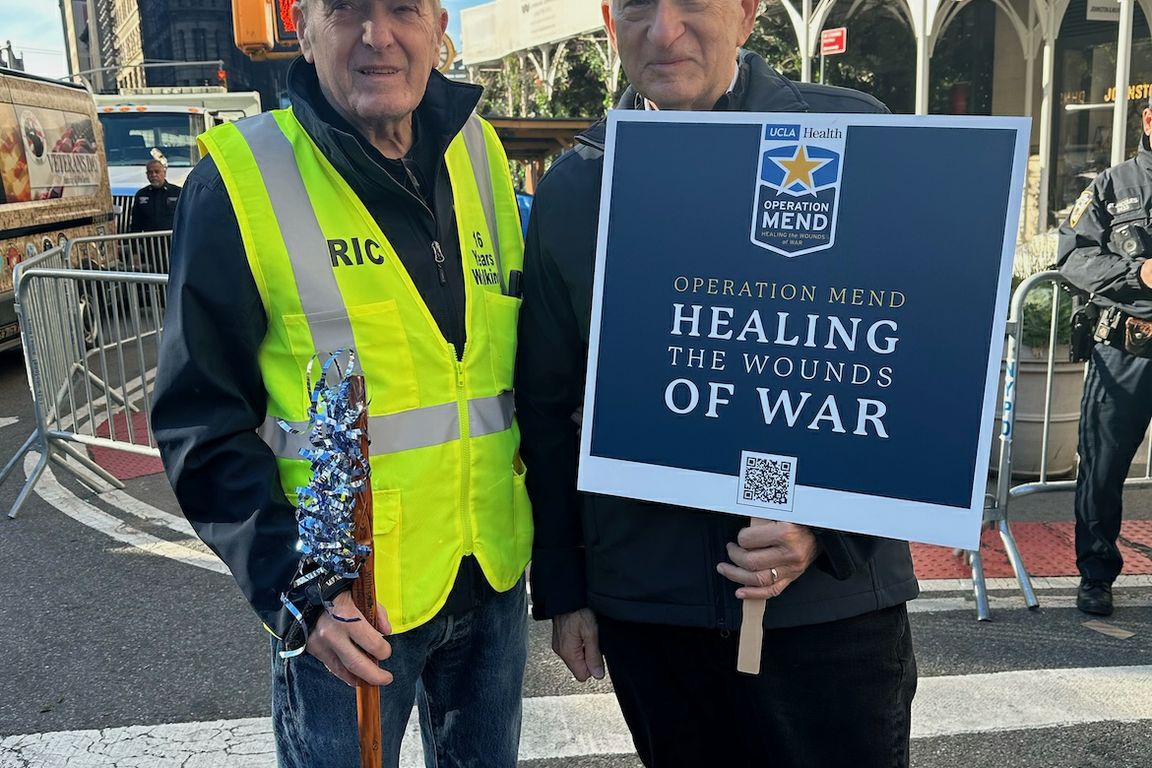 Chancellor Gene Block, holding sign, stands with a military veteran at the New York City Veterans Day parade