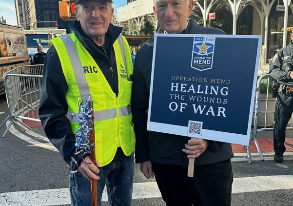 Chancellor Gene Block, holding sign, stands with a military veteran at the New York City Veterans Day parade