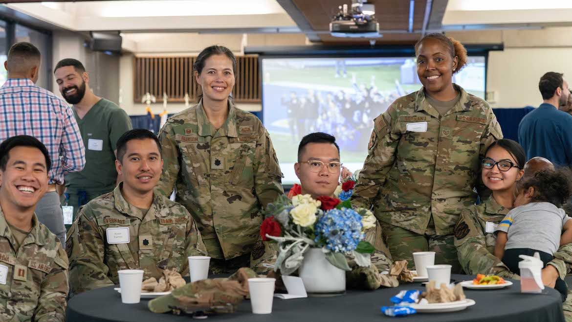 Six UCLA military service members in fatigues seated at luncheon table