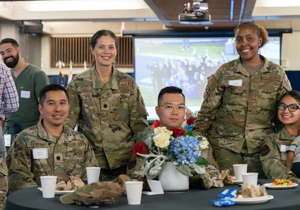 Six UCLA military service members in fatigues seated at luncheon table