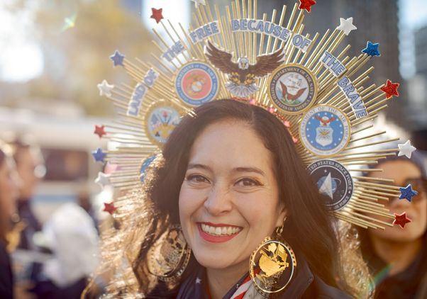 Smiling woman with a crown reading ‘Land of the free because of the brave’ at New York City Veterans Day parade