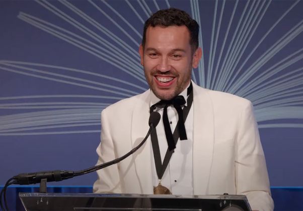 Justin Torres at podium in a white jacket giving speech at National Book Awards ceremony