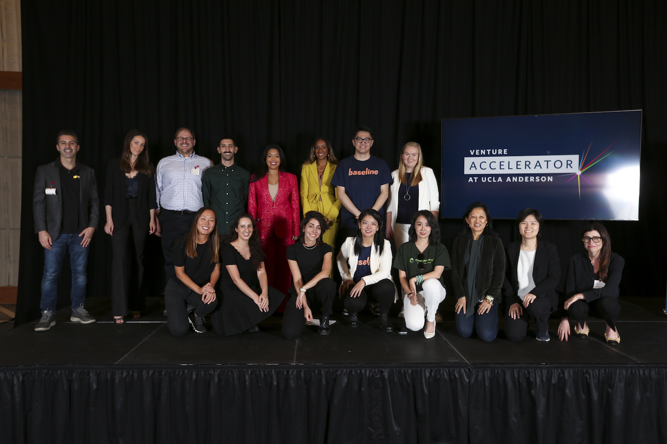 16 people in two rows on stage.