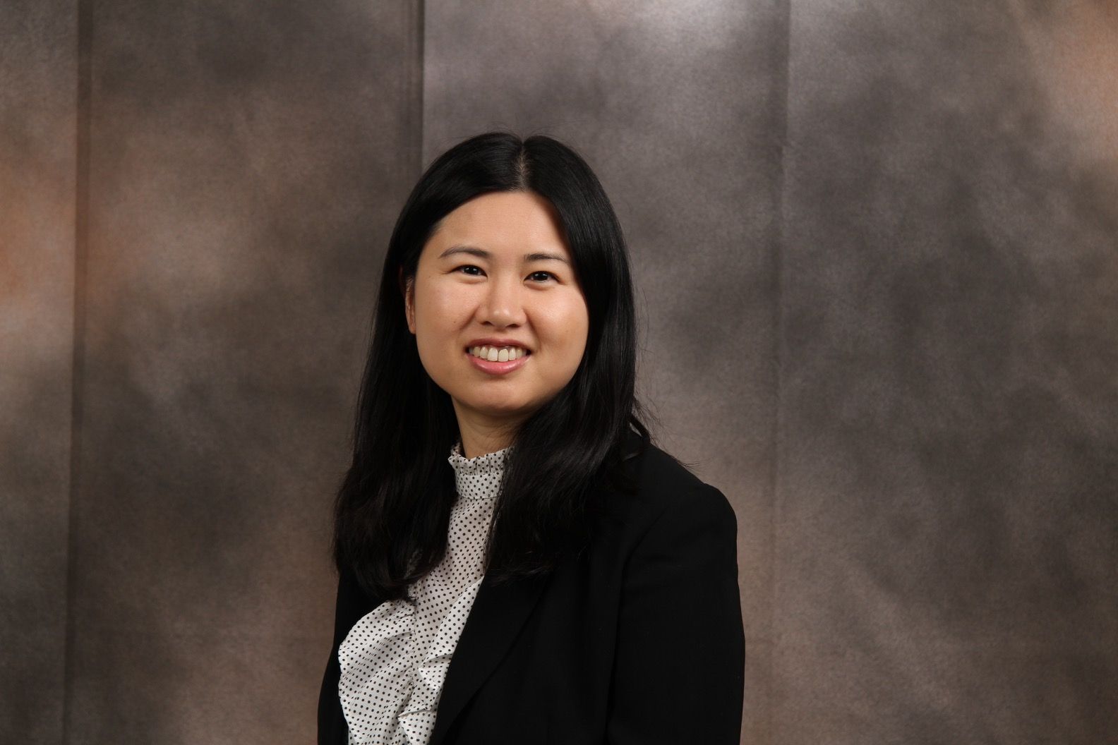 Lucinda Leung wearing a white ruffled top and black jacket