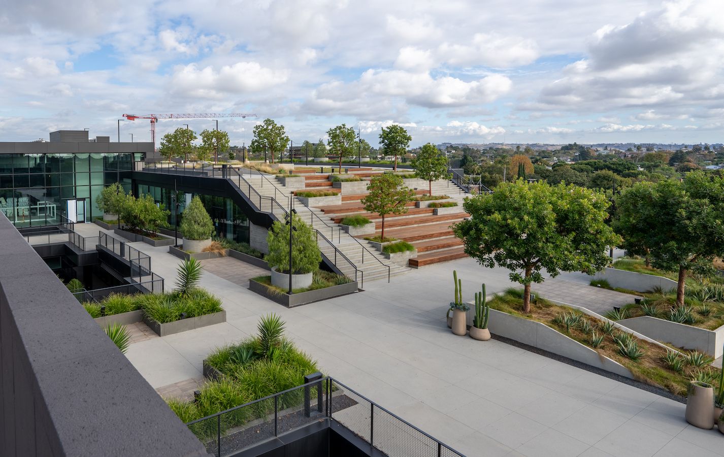 Wide shot of back of properties with patio, terraced benches and construction crane