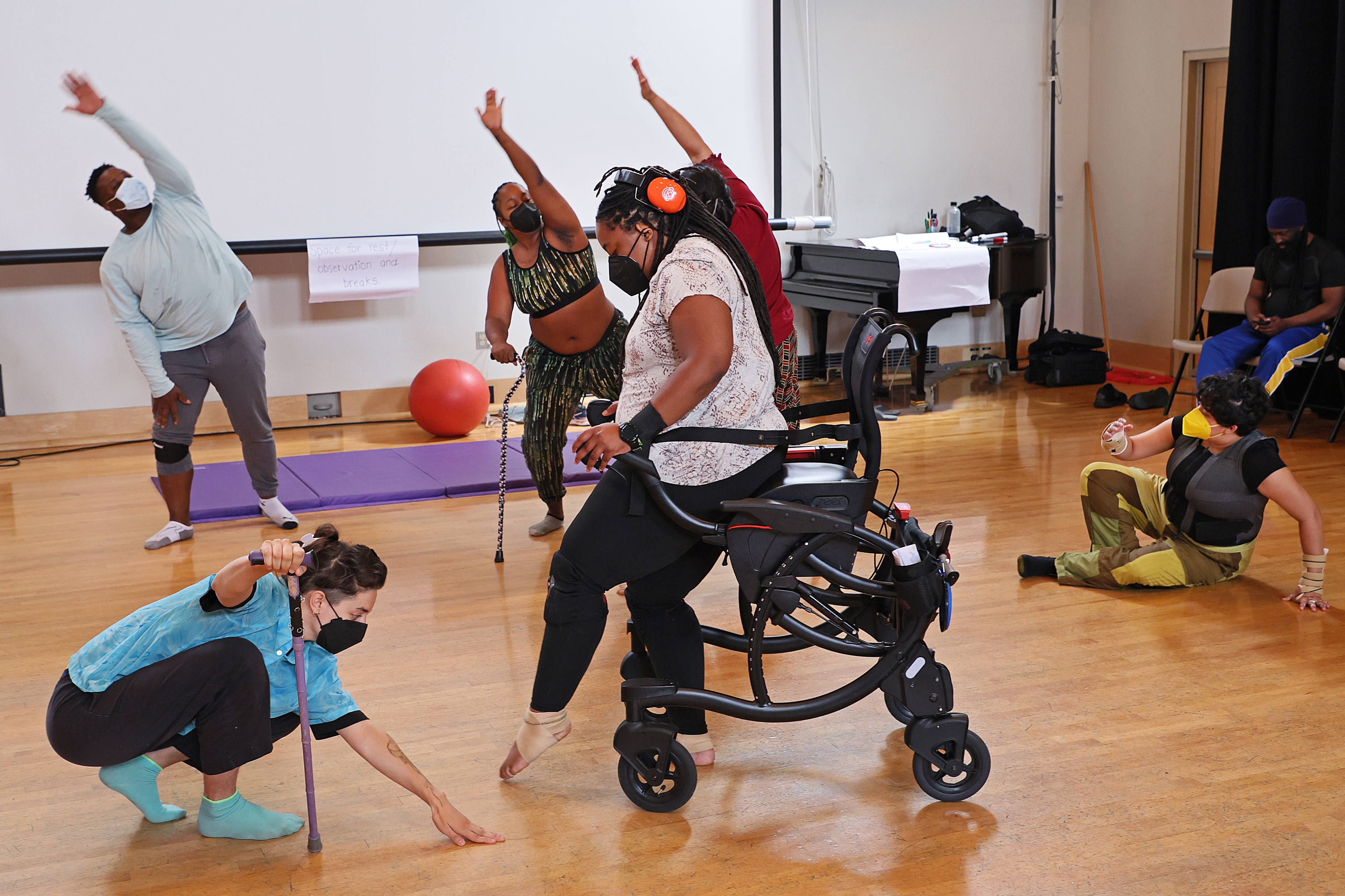 Disabled dancers in motion, some with raised arms, one standing with a walker