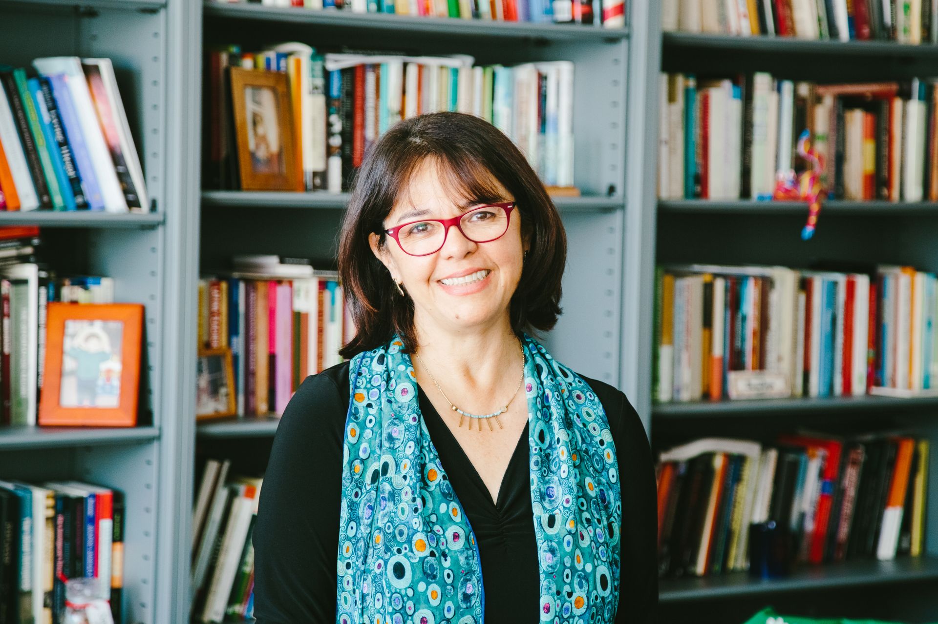 Cecilia Menjívar standing in front of shelves full of books