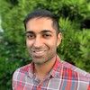Headshot of Bharat Venkat wearing a plaid shirt, photographed outdoors.