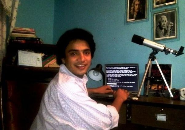 Abraham Amiri sits and a desk with a laptop and small telescope