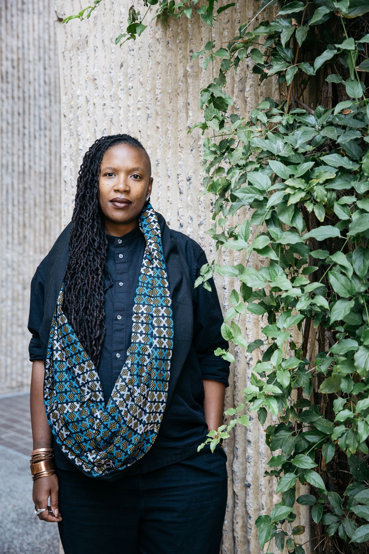 E. Tendayi Ahciume standing in front of wall with ivy