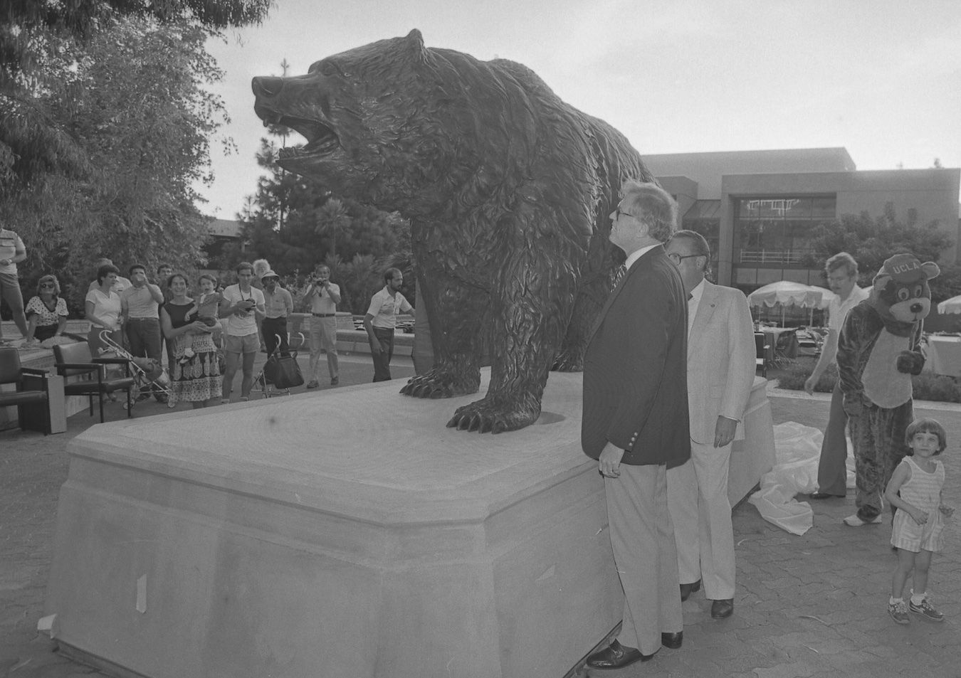 Chancellor Young stands next to “The Bruin” statue, surrounded by others