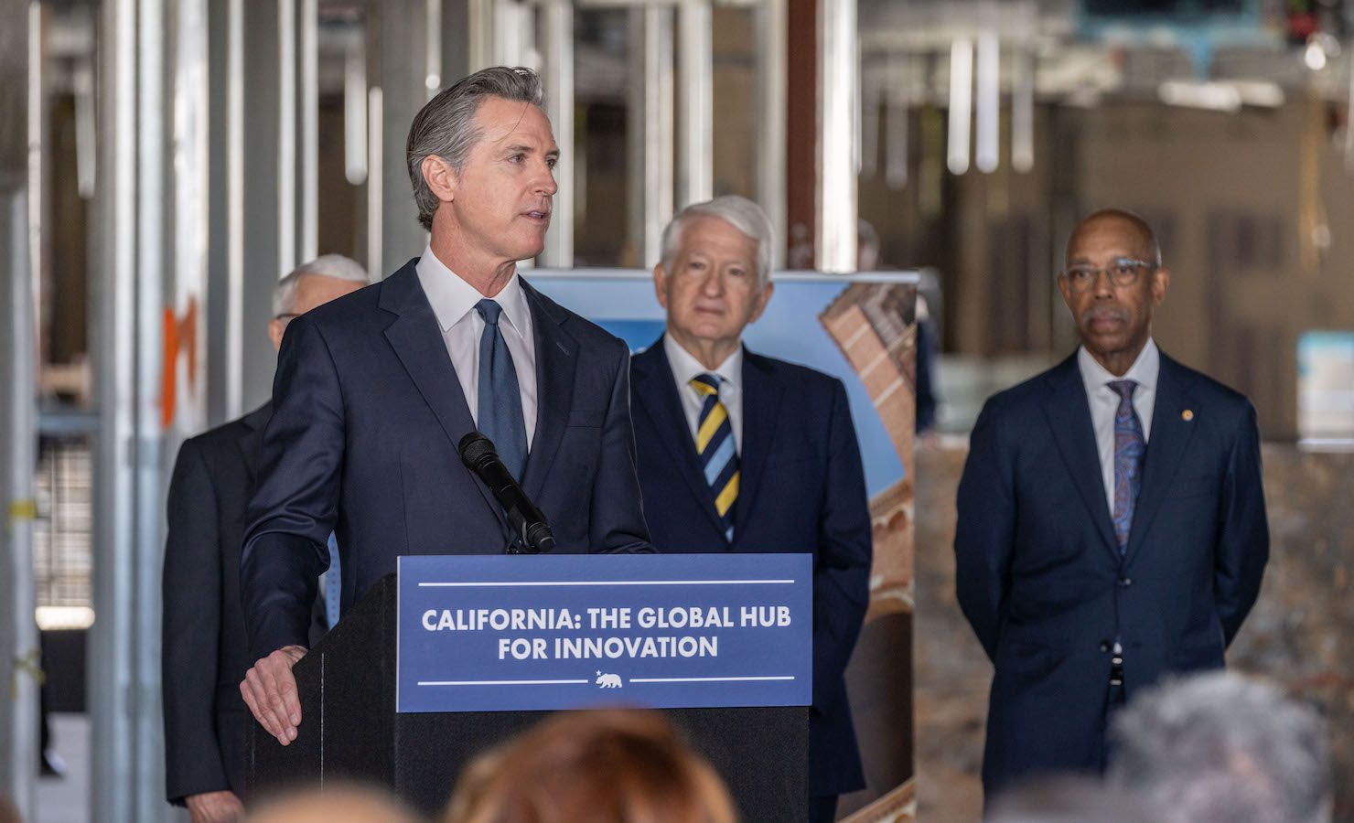 California Gov. Gavin Newsom speaks at podium at the Jan. 3 press conference, with Chancellor Block and UC President Michael Drake behind him