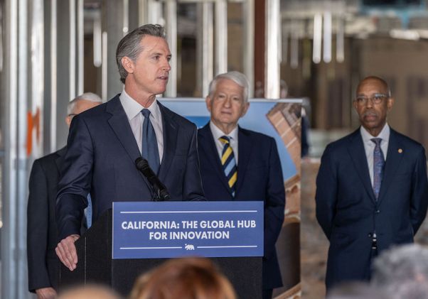 California Gov. Gavin Newsom speaks at podium at the Jan. 3 press conference, with Chancellor Block and UC President Michael Drake behind him