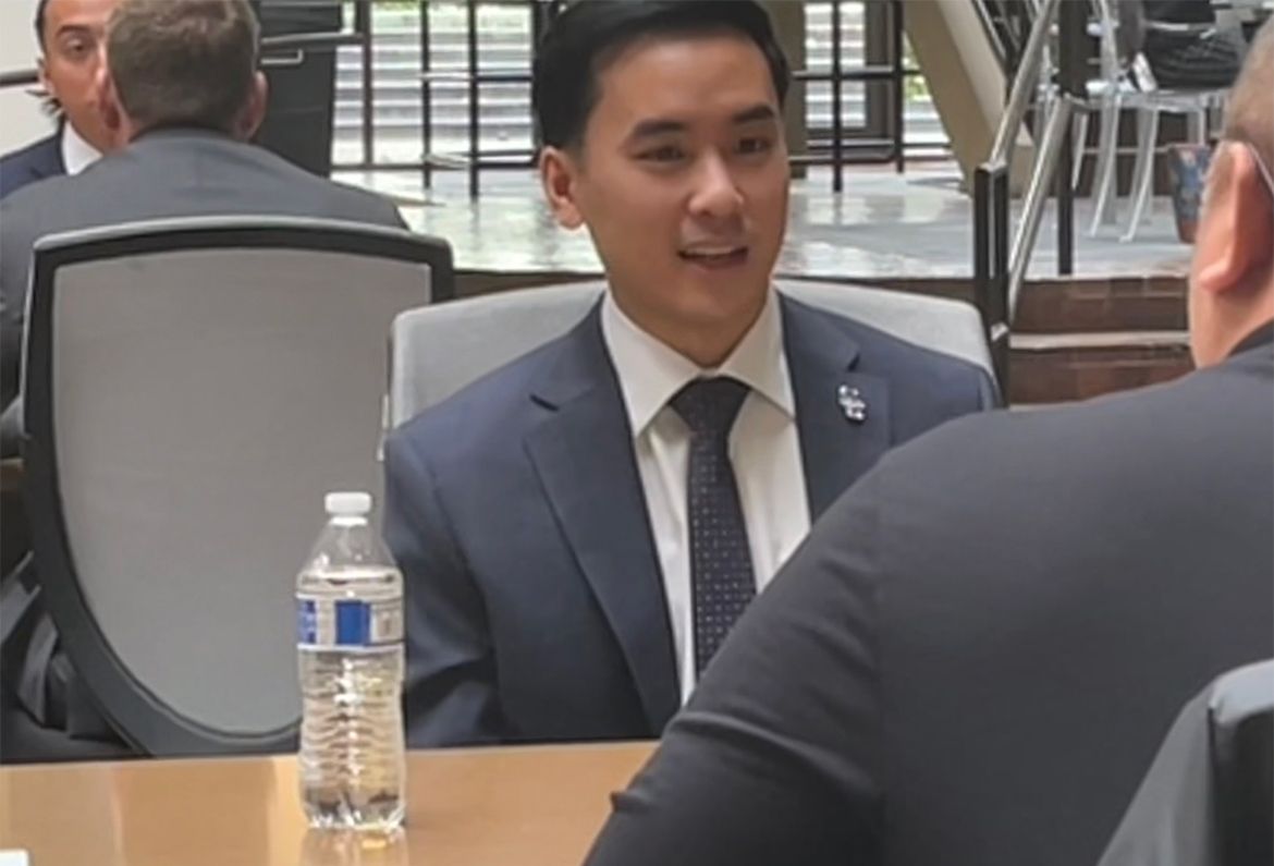 Jimmy Phan seated at a desk in suit and tie 