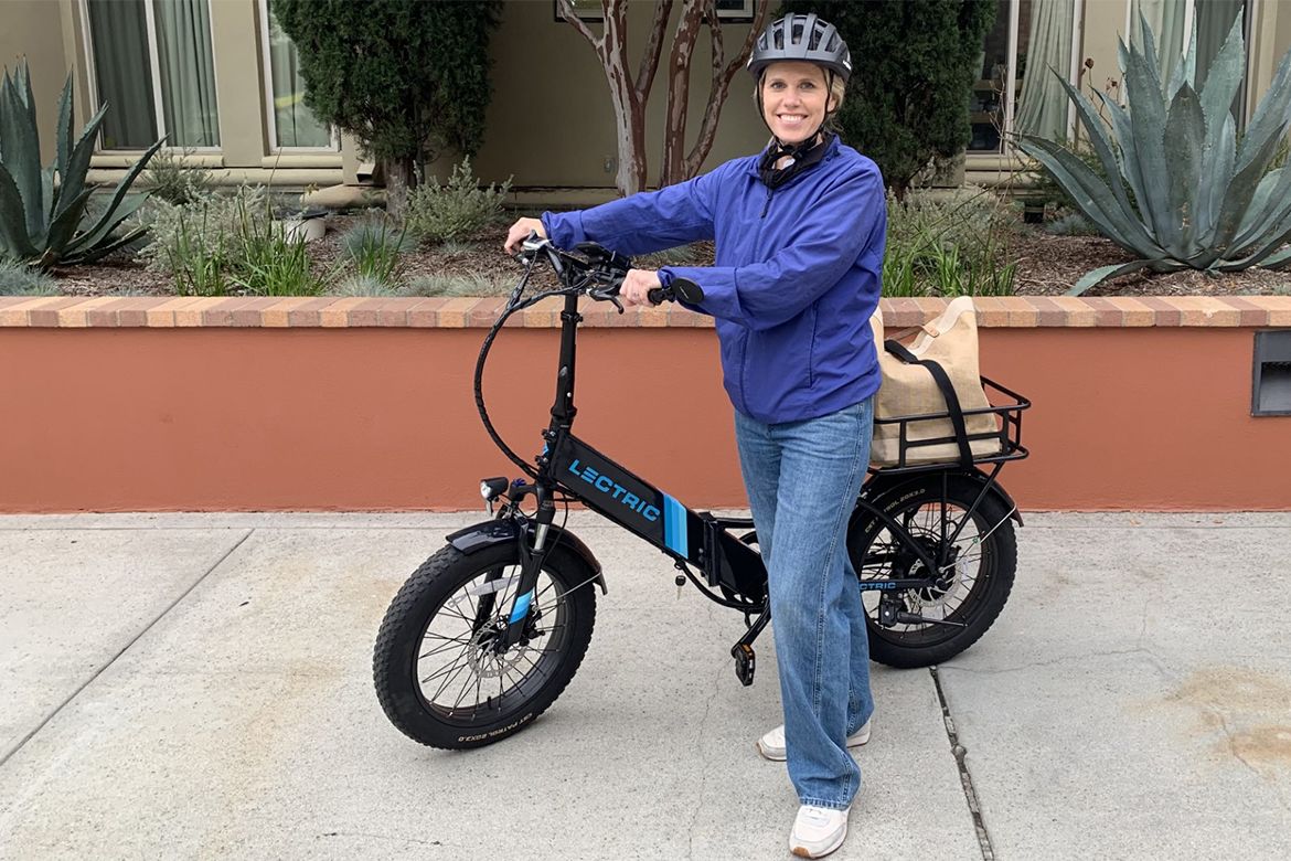 Person wearing blue jacket holding electric bike