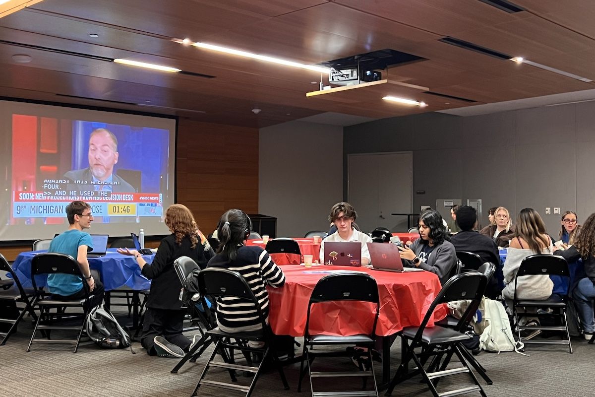 Election night watch party — students sit at several tables as TV screen displays results of 2024 elections
