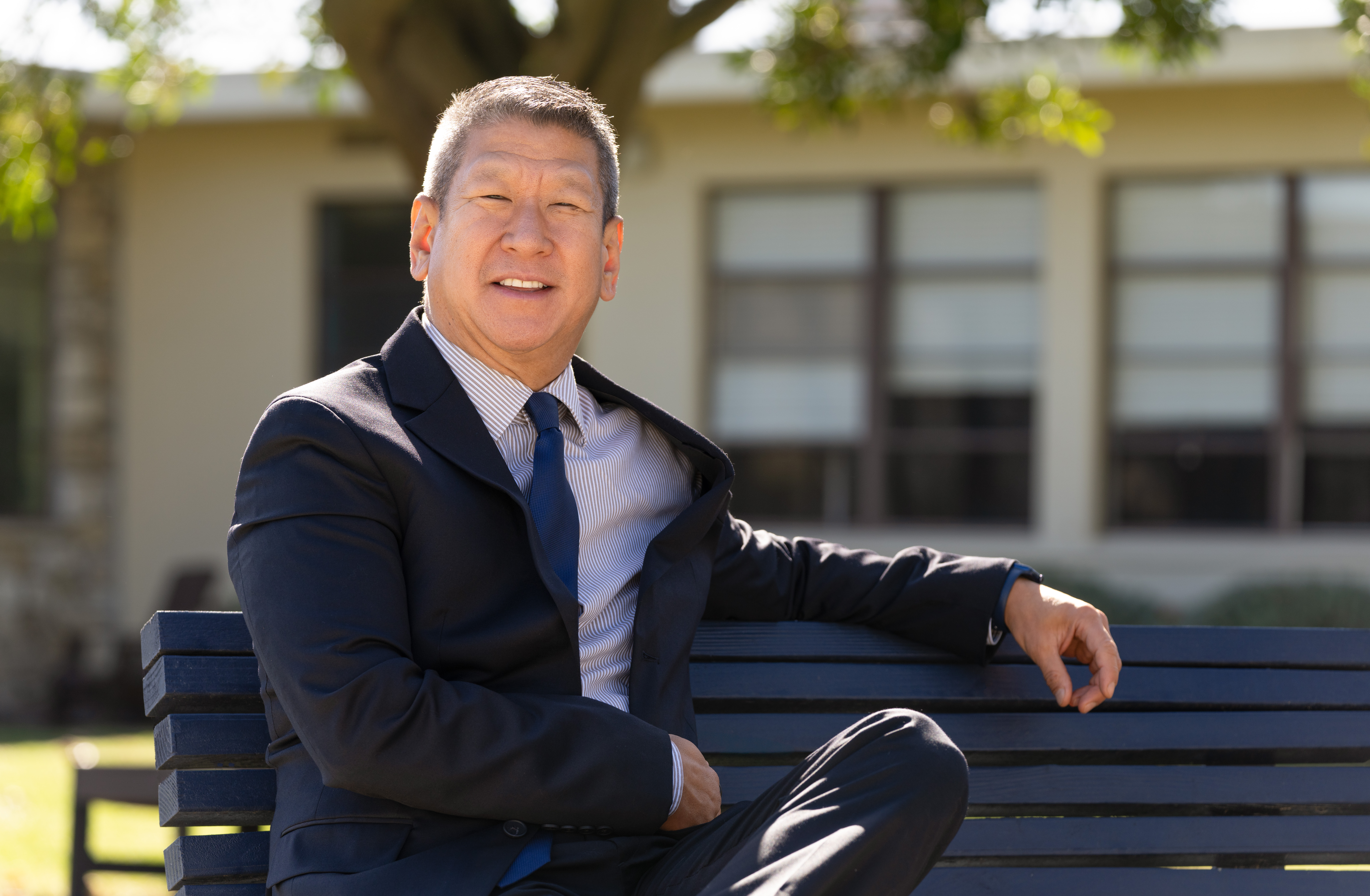 Steve Yu in suit and tie sitting on a bench outdoors