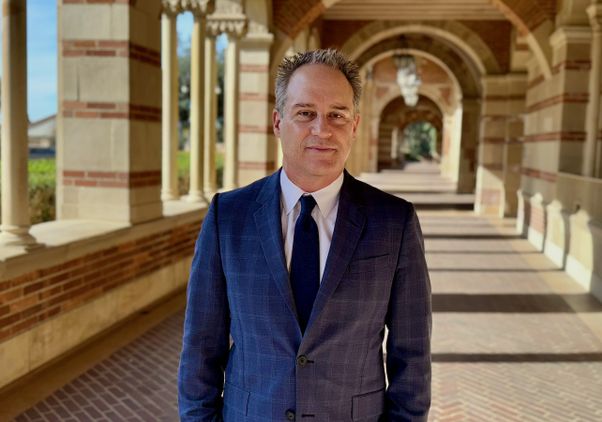 Brian Kite — waist-up photo in suit, standing in Royce Hall portico