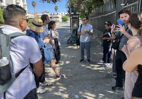 UCLA faculty member Gustavo Leclerc and students speaking on sidewalk near bus stop