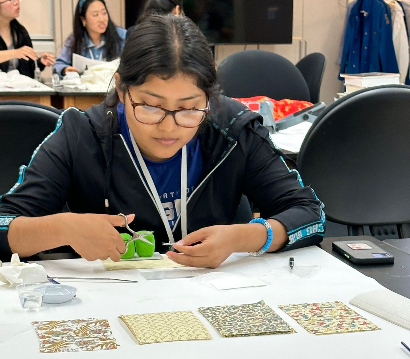 Irene Gonzalez, seated at a table, holds scissors