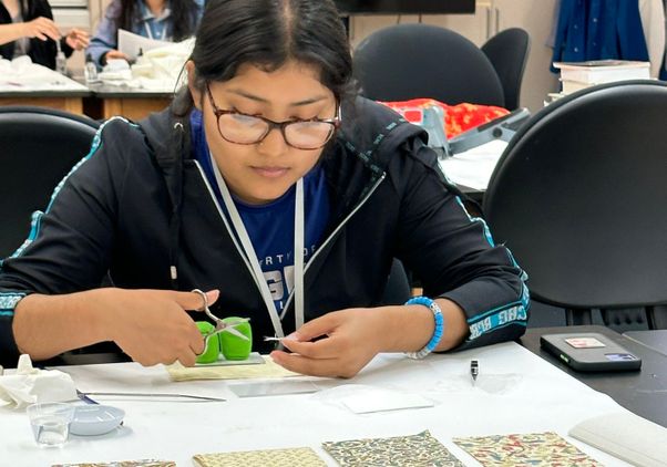 Irene Gonzalez, seated at a table, holds scissors