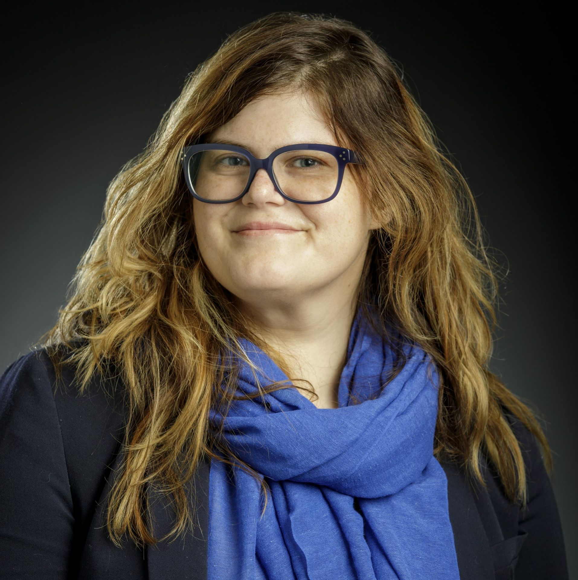 Portrait of Jaimie Krems wearing glasses and blue scarf