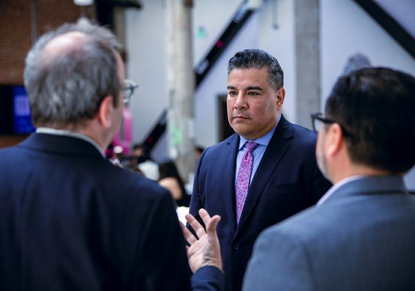 California Insurance Commissioner Ricardo Lara speaks with two attendees at the policy briefing