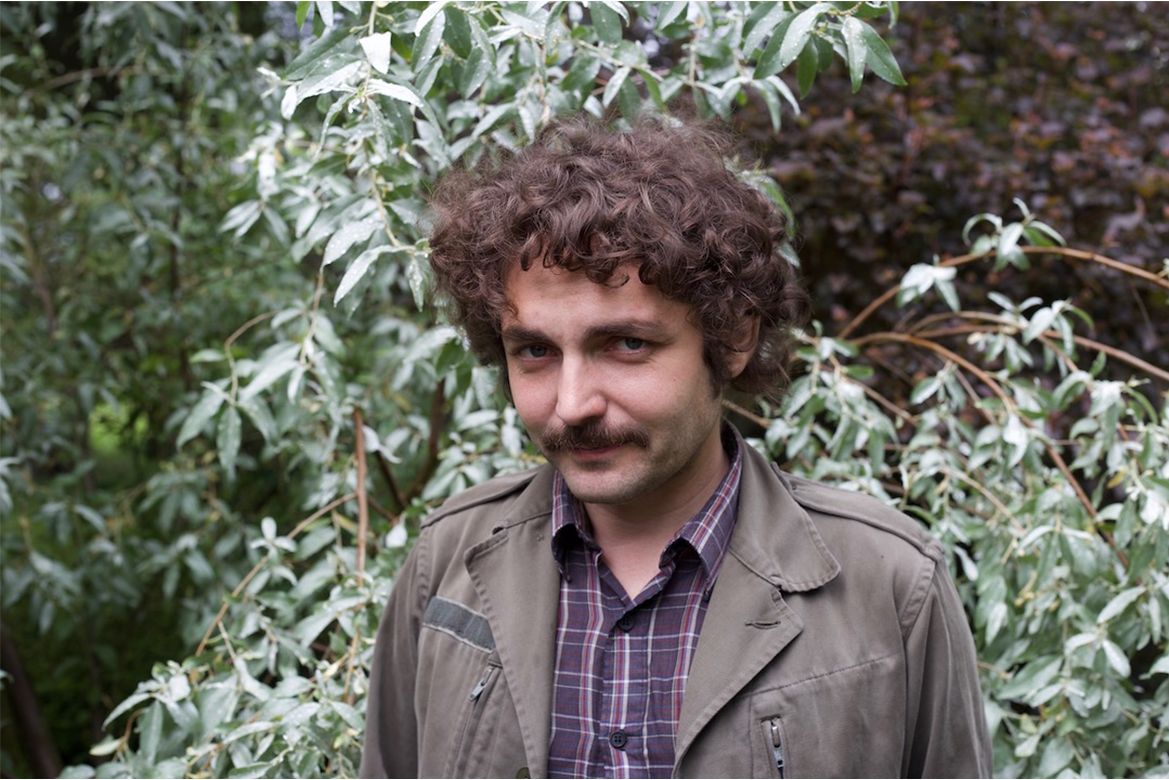 Boris Dralyuk in front of green foliage