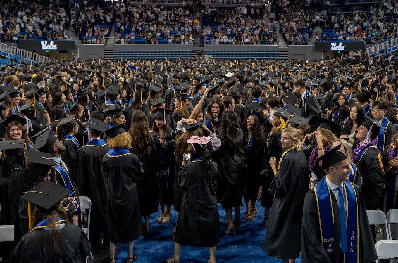 Wideshot of graduating students celebrating on floor of Pauley Pavilion