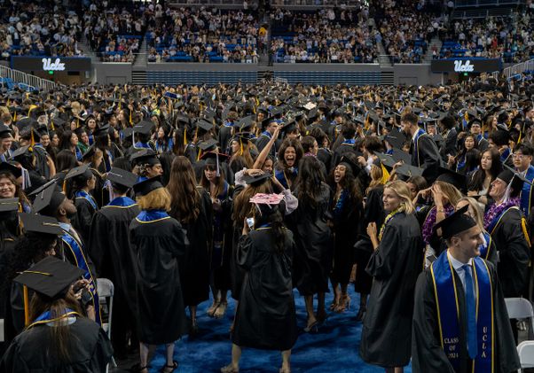 Wideshot of graduating students celebrating on floor of Pauley Pavilion
