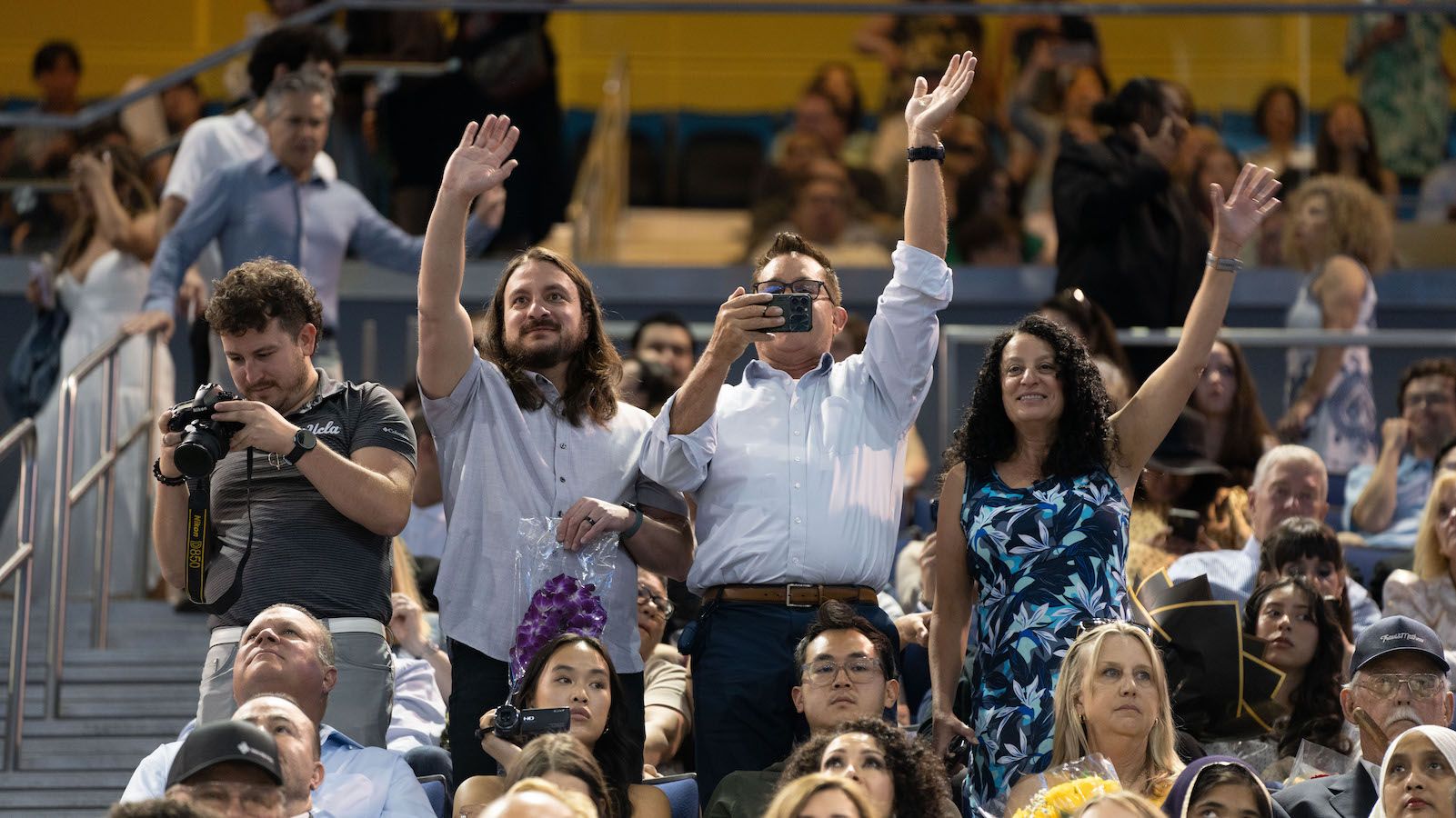 Family members wave to graduating students from the crowd