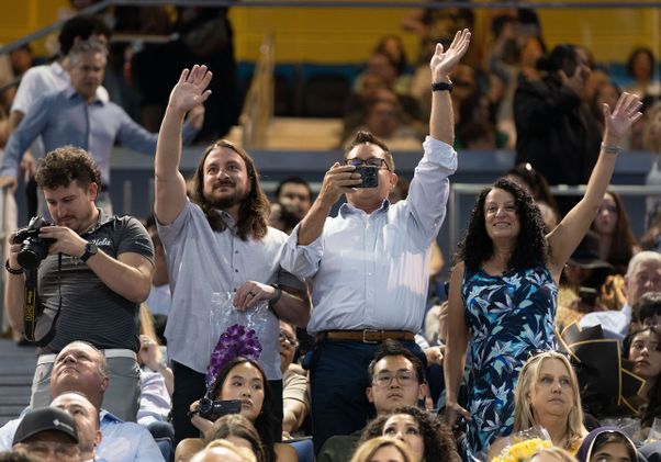 Family members wave to graduating students from the crowd