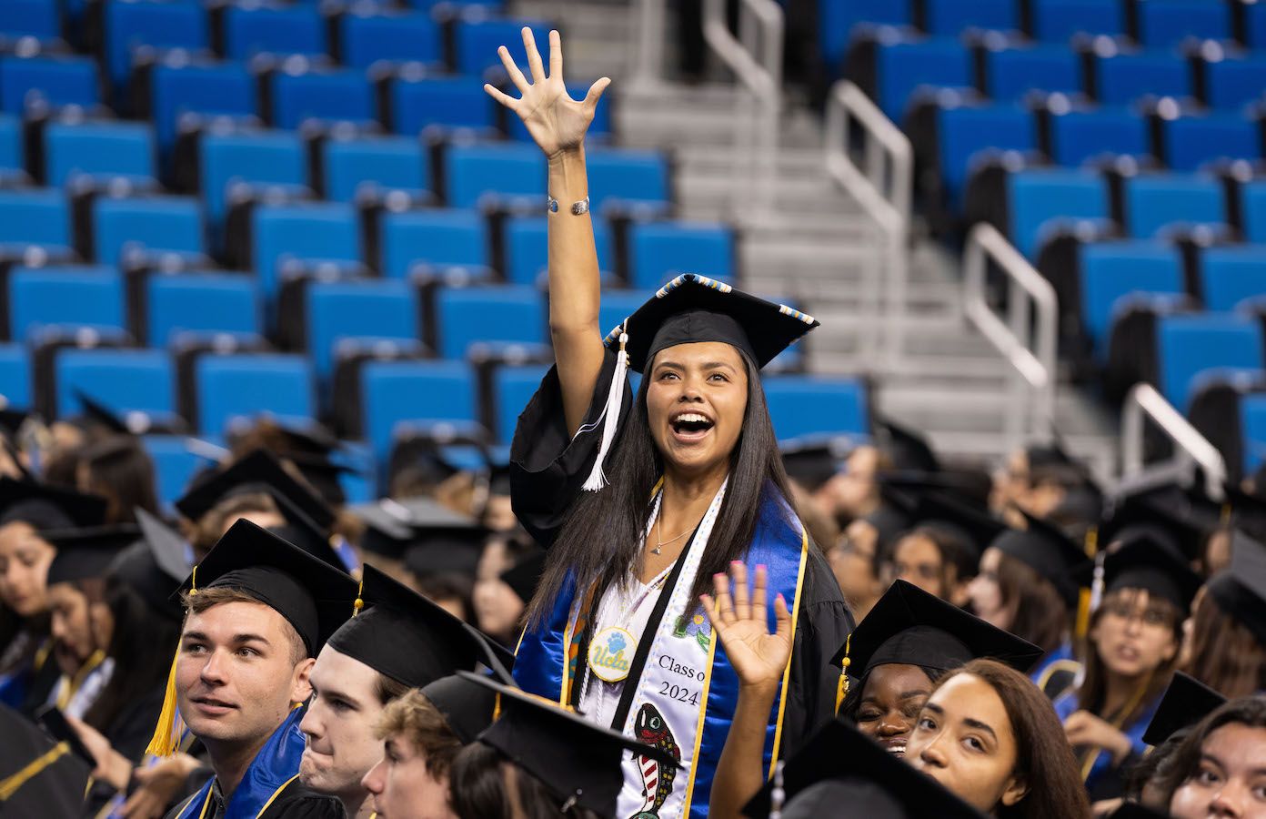 Graduating student waves from the crowd in Pauley Pavilion